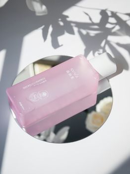 10 Home Remedies for Glowing Skin A stylish pink toner bottle placed on a mirror with artistic shadows.
